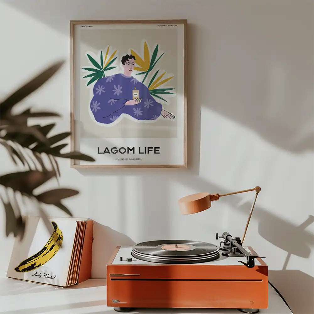 Modern poster titled "Lagom Life" featuring a person in a purple robe surrounded by green leaves, displayed above a record player in a stylish interior setting.