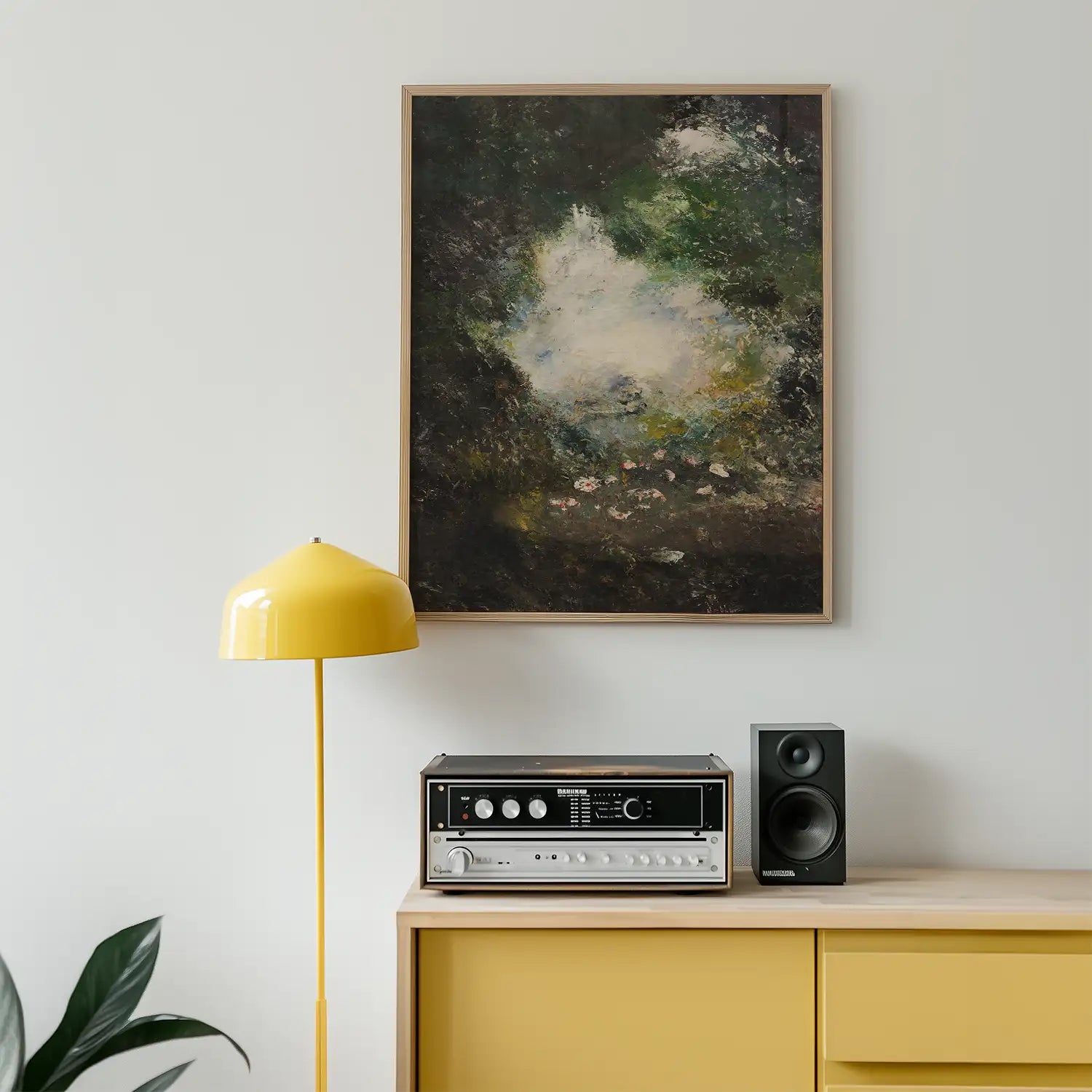Abstract landscape painting with a dark background and hints of green and light, framed and displayed above a yellow lamp and a vintage audio system on a wooden cabinet.