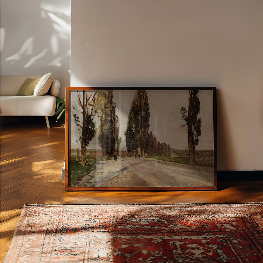 Framed painting of a tree-lined path displayed on the floor next to a beige sofa and an area rug.