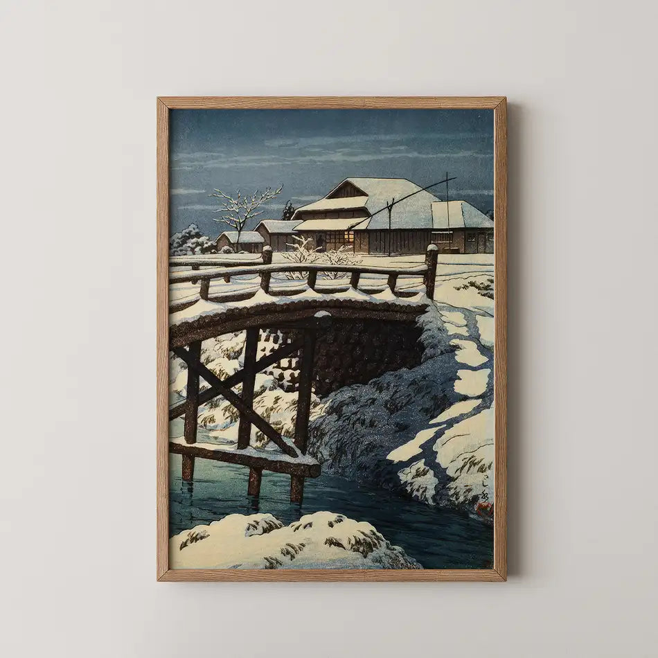 Framed painting of a snow-covered bridge and traditional houses under a night sky.