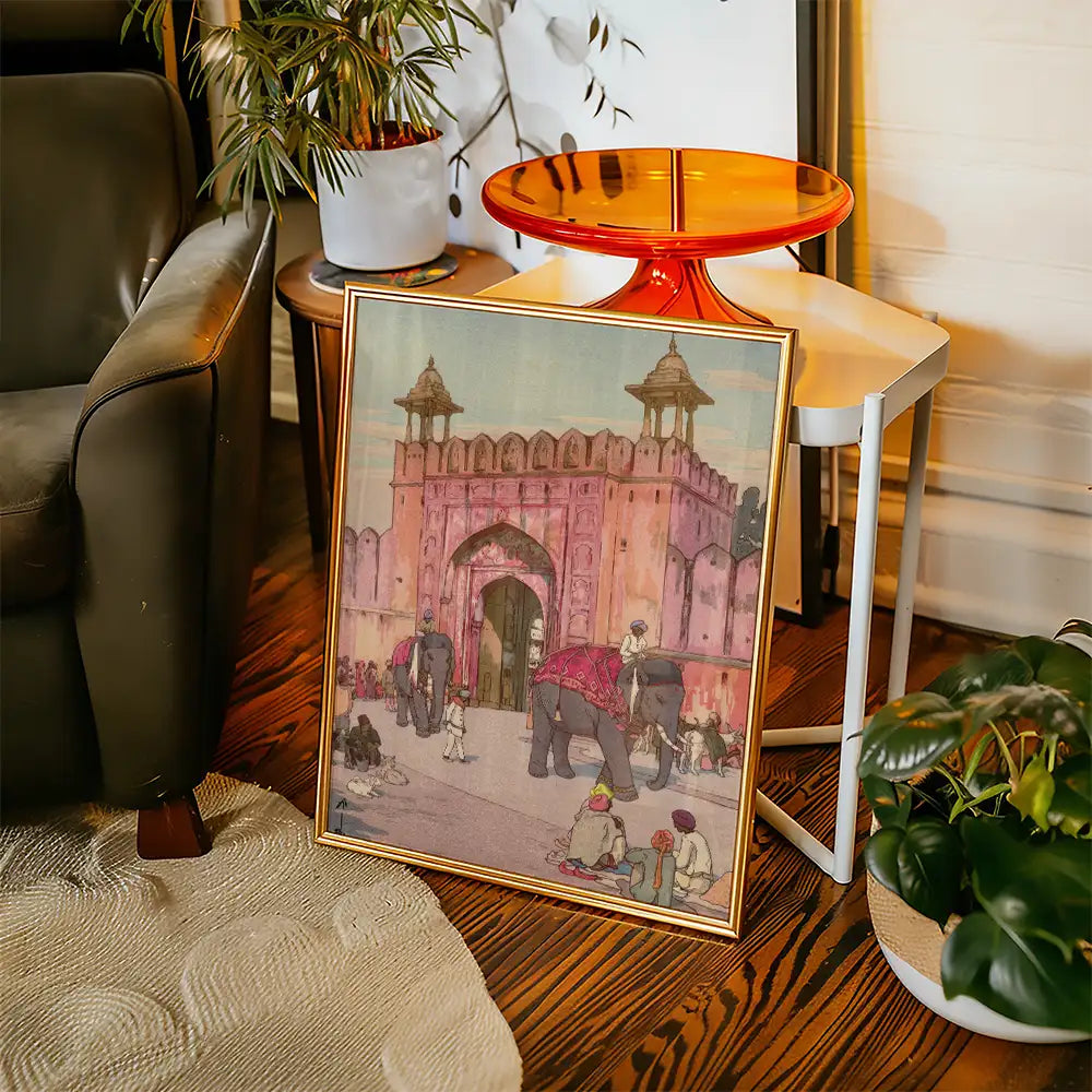 Framed painting of a historic pink fort with elephants, people, and vibrant colors, displayed in a cozy living space.