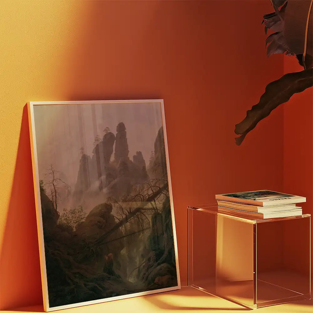 Framed painting of a misty mountain landscape leaning against an orange wall, accompanied by a stack of books on a clear acrylic side table.