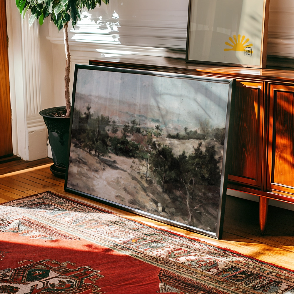 Framed landscape painting leaning against a wooden sideboard with a potted plant and a colorful rug in a well-lit room.