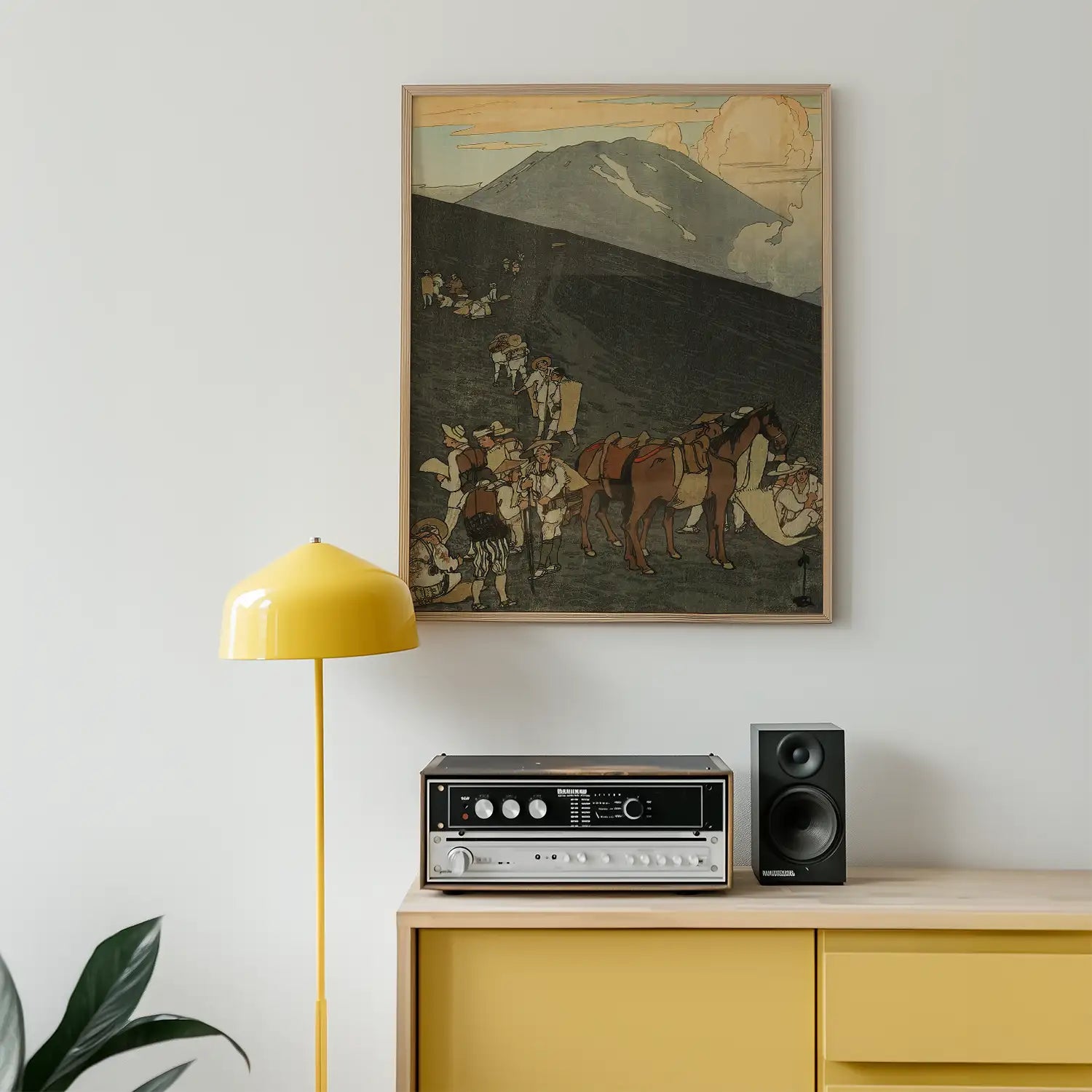 Vintage-inspired painting of people and horses on a hillside, framed and displayed above a yellow floor lamp and a retro audio setup on a yellow cabinet.