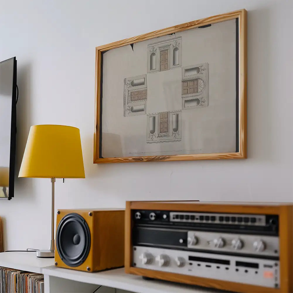 Framed architectural print hanging on the wall above a yellow lamp and vintage audio equipment.