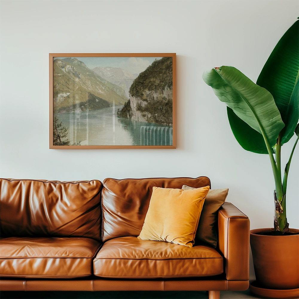 Framed landscape painting above a brown leather sofa with a yellow pillow and a large green plant in a pot.