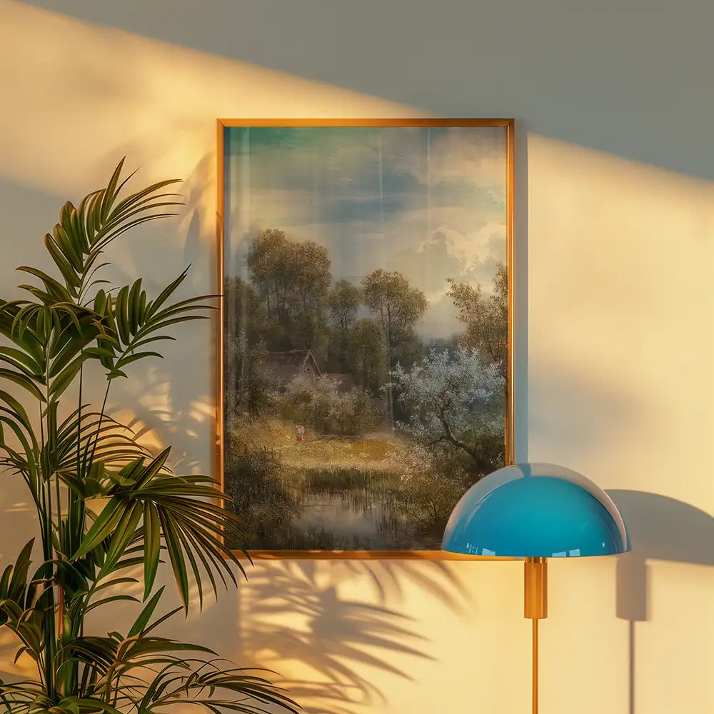 A serene landscape painting framed in gold, depicting a peaceful scene with trees, a small house, and a figure by a pond, illuminated by soft sunlight against a wall with a stylish blue lamp and greenery.