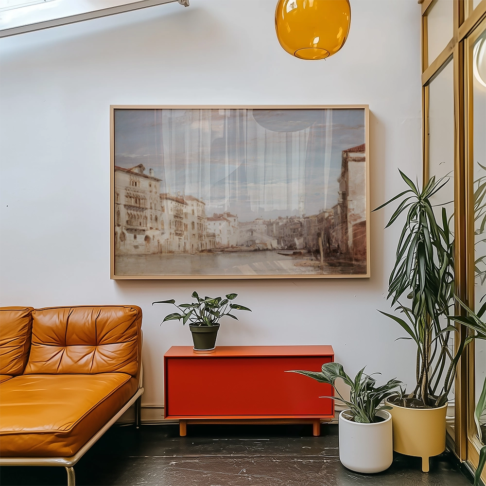 A framed painting of a picturesque canal scene hanging above a red cabinet in a modern living space with orange couch and potted plants.