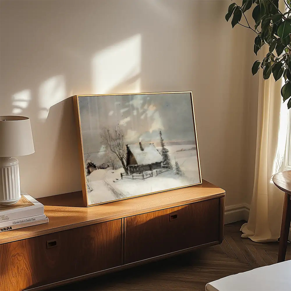 Winter landscape painting featuring a snow-covered cottage displayed on a wooden cabinet in a cozy interior setting.