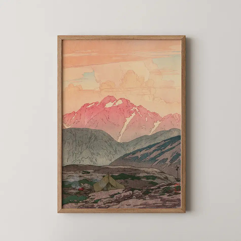Framed painting of a mountainous landscape at sunset with pink and orange hues in the sky and a green tent in the foreground.