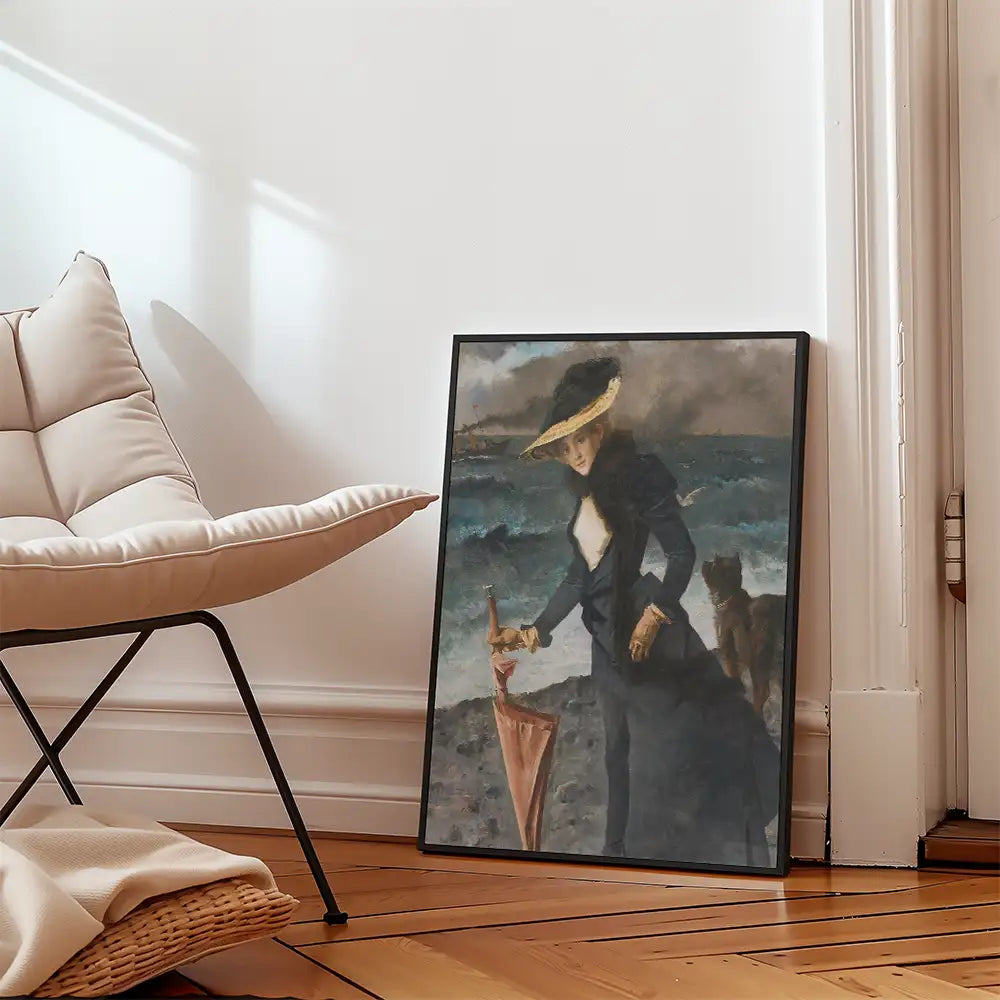 Painting of a woman holding an umbrella by the shore, with a cat beside her, framed and placed beside a modern chair in a sunlit room.