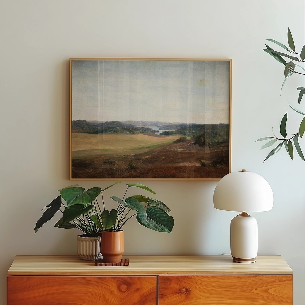 Landscape painting displayed over a wooden console table with a potted plant and a lamp in a modern interior setting.