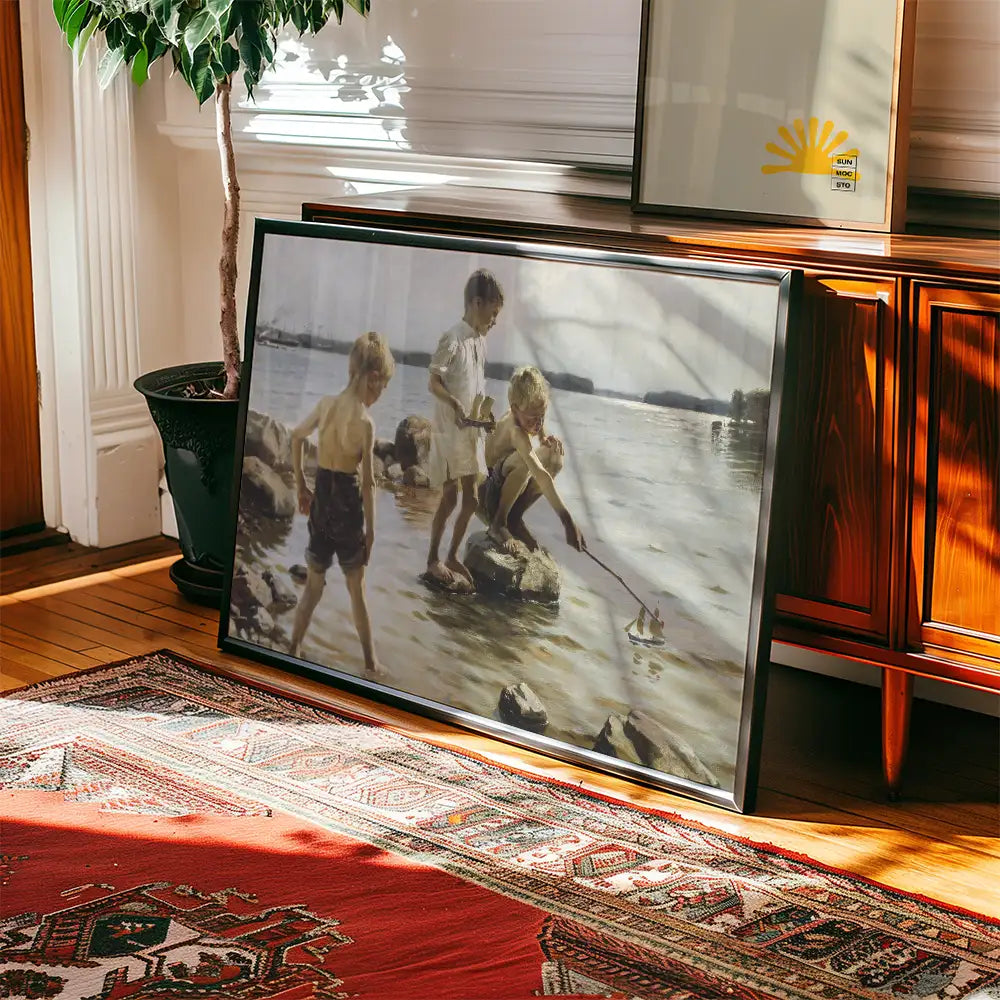 Framed painting of three children playing by the water's edge, with a colorful rug and plant in a sunny interior setting.