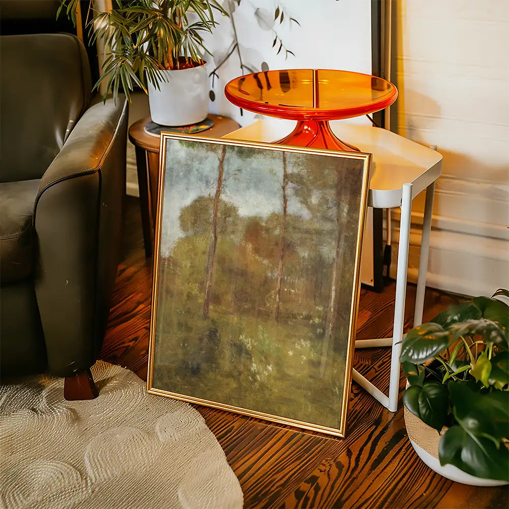 Framed landscape painting displayed beside a modern side table and houseplants in a cozy living room setting.