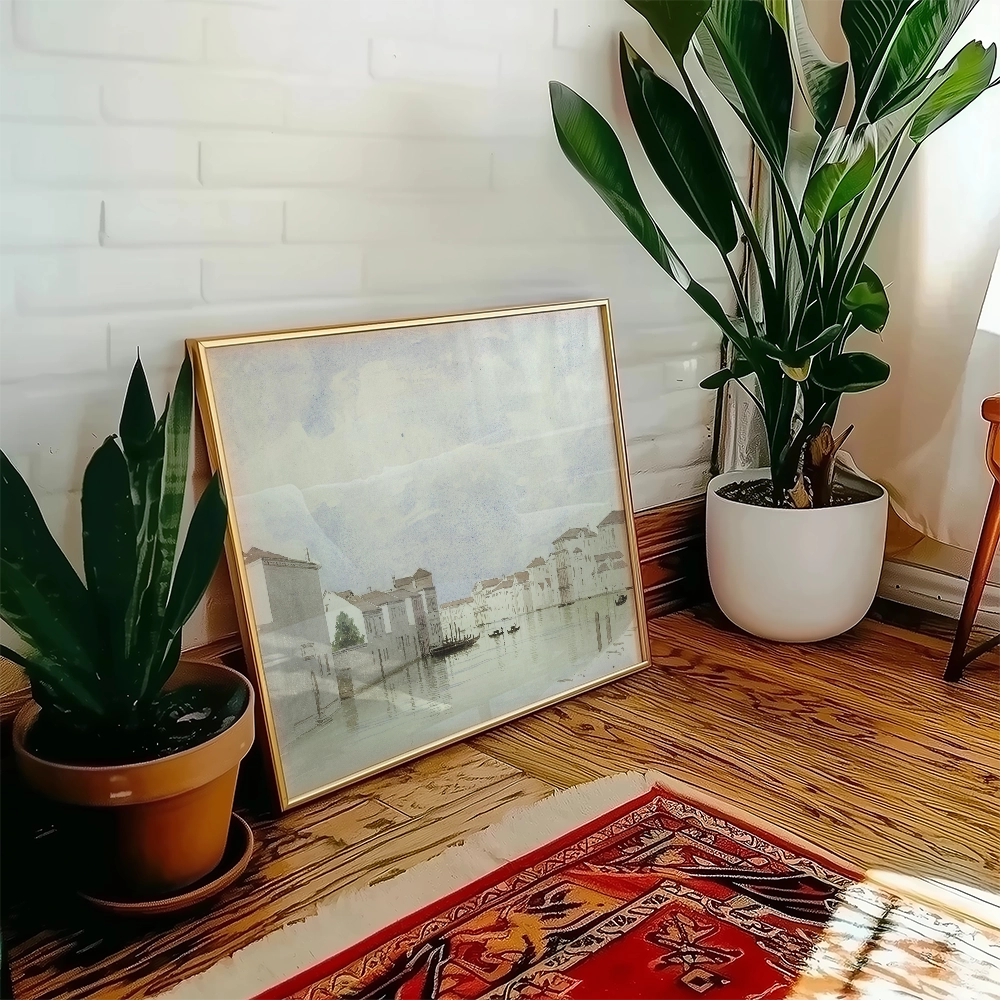 Framed painting of a serene waterfront scene leaning against a wall, surrounded by potted plants and a colorful rug.