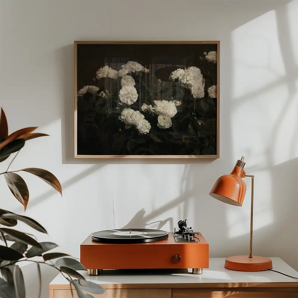 A framed painting of white flowers against a dark background, displayed above an orange turntable and lamp in a bright, modern room.