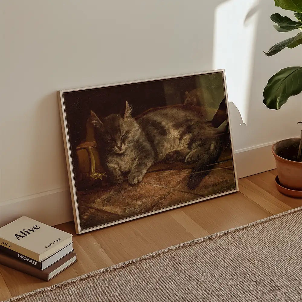 Framed painting of a sleeping gray cat, positioned against a wall with potted plant and books nearby.