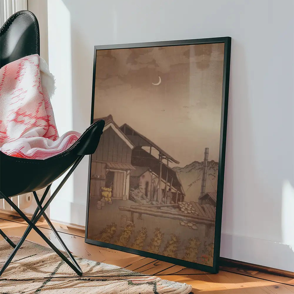 Framed vintage landscape painting featuring a mountain scene with a crescent moon, leaning against a black chair in a cozy interior setting.