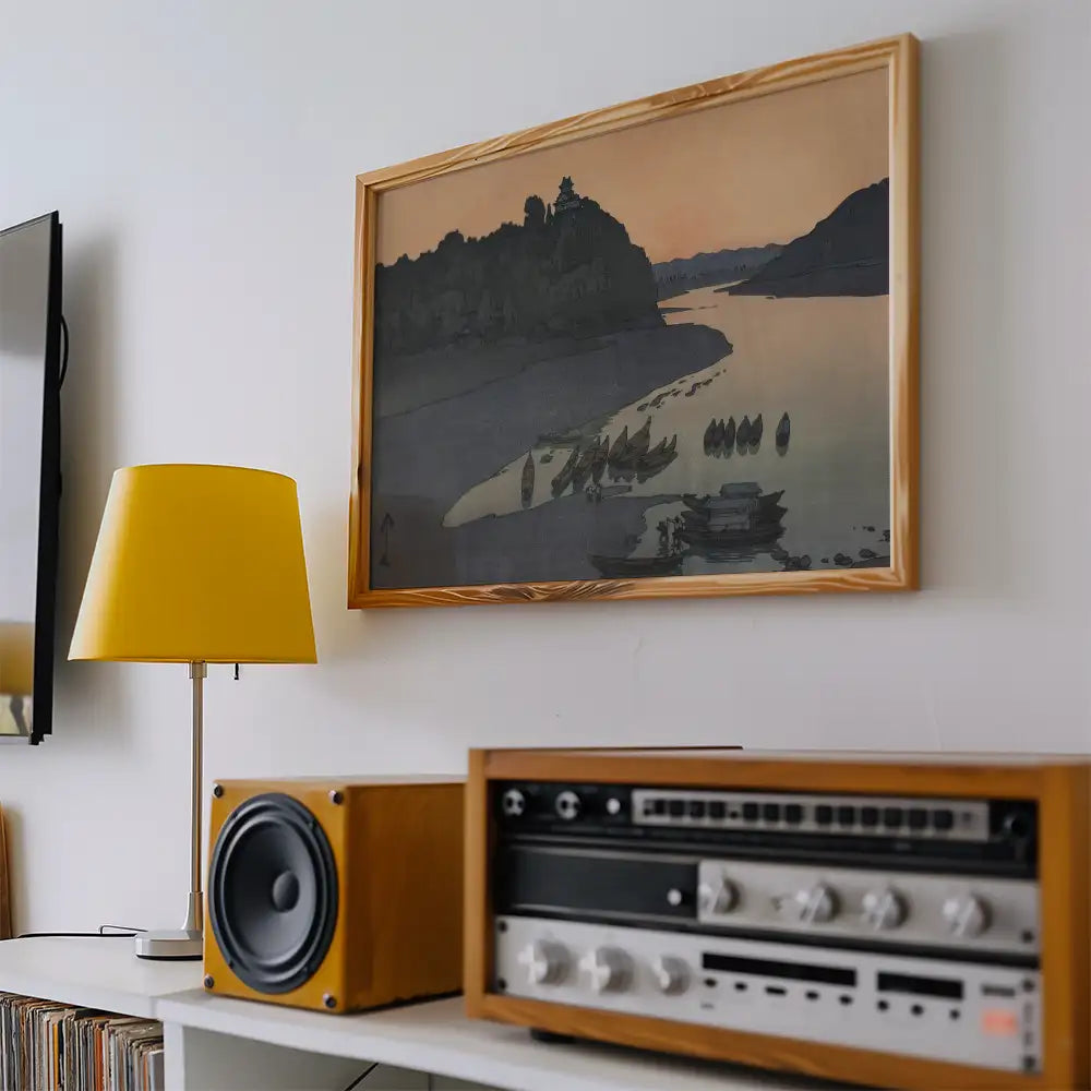 Framed landscape painting on a wall with a yellow lamp and vintage audio equipment in a modern interior setting.