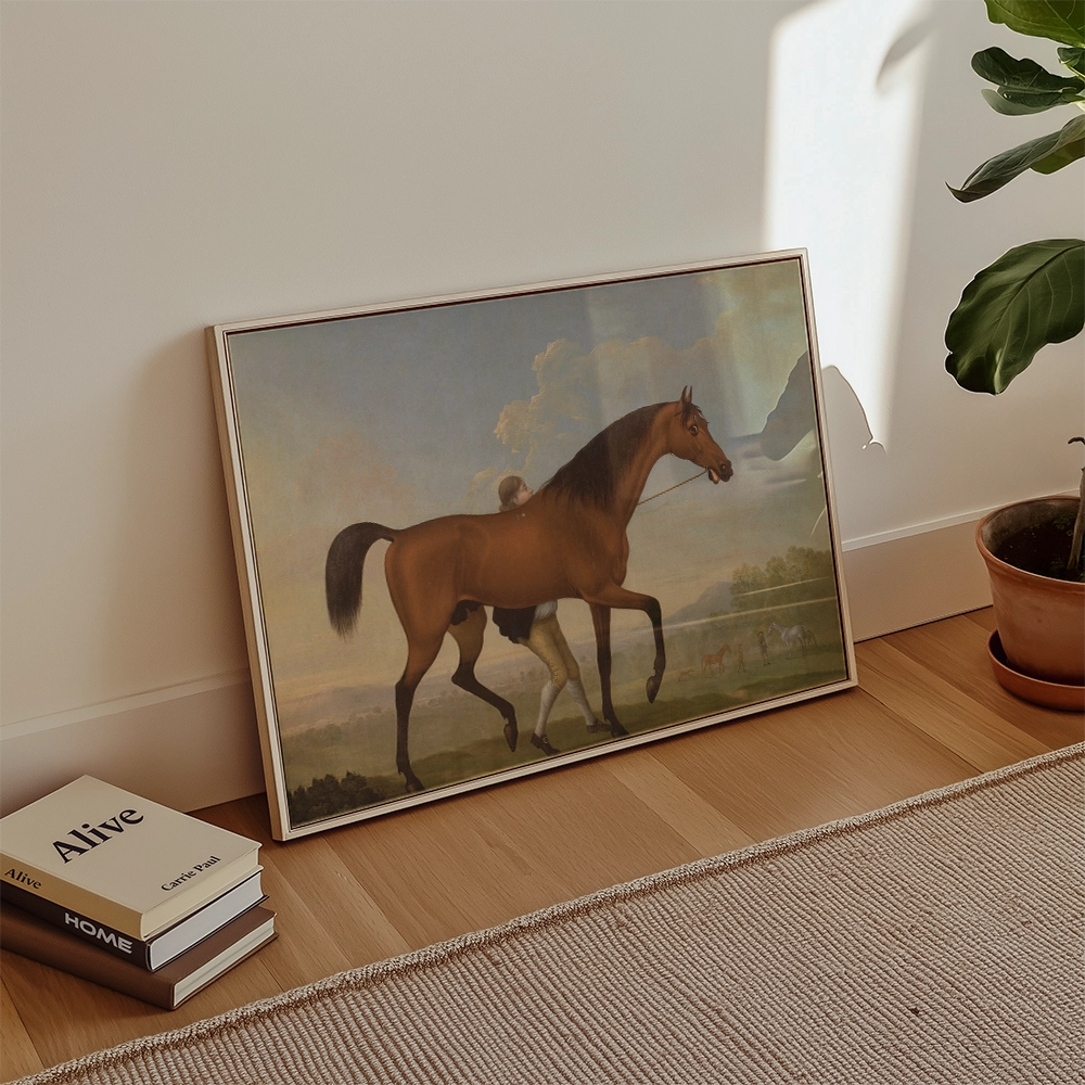Framed painting of a horse and rider in a serene landscape, leaning against a wall beside books and a potted plant.