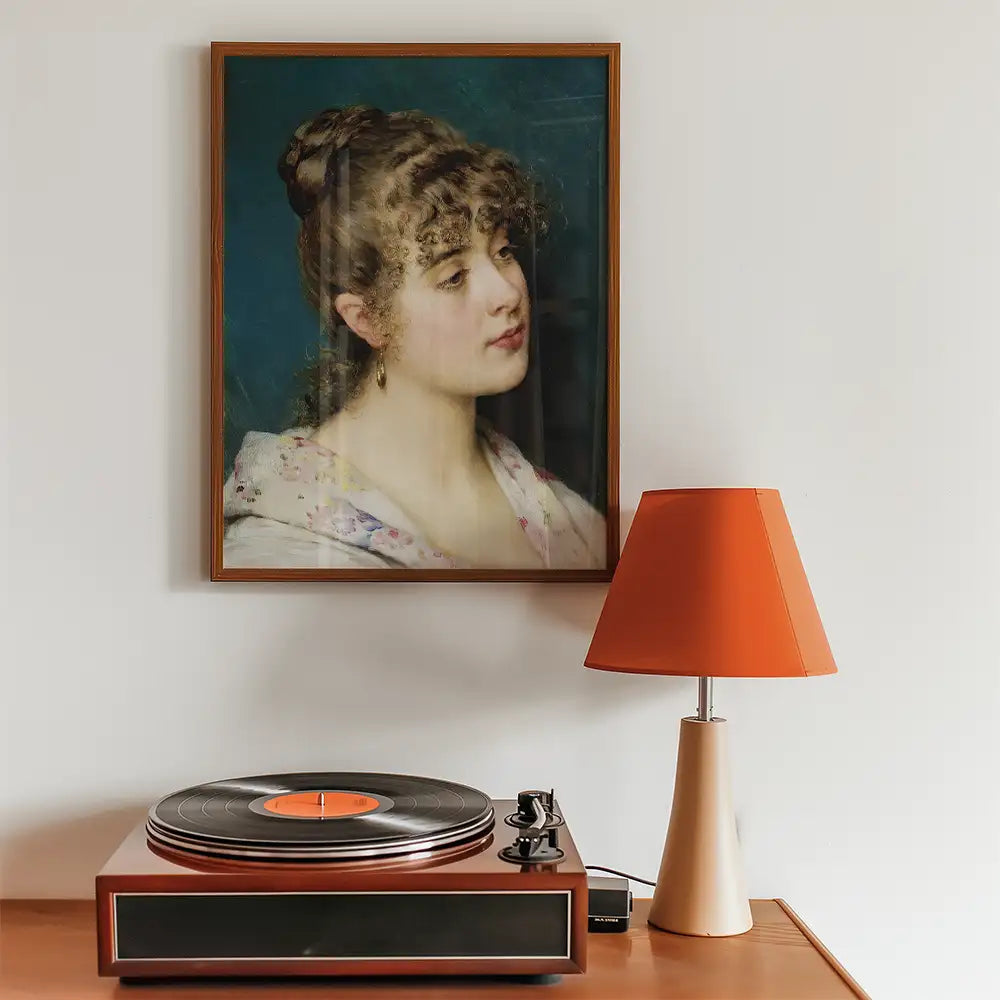 Portrait painting of a young woman displayed in a wooden frame above a vintage turntable and an orange lampshade.