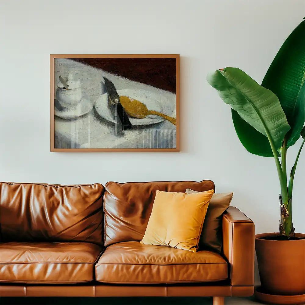 A framed painting of a table setting featuring a white cup, a plate with a gold spoon, and a black knife, displayed above a brown leather sofa with a yellow cushion, adjacent to a large green plant.