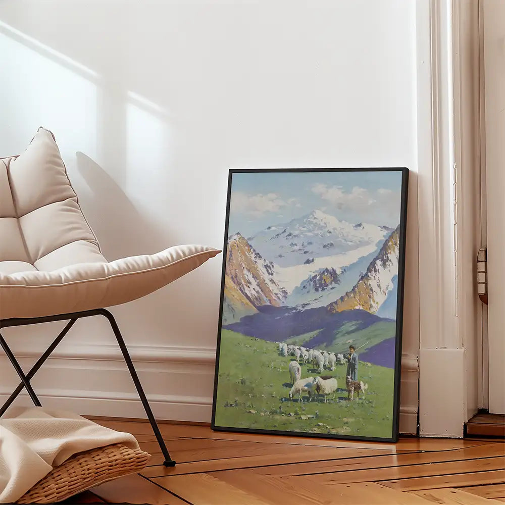 Landscape painting of a scenic mountain view with sheep grazing in a green meadow, framed and leaning against a wall in a modern living space.