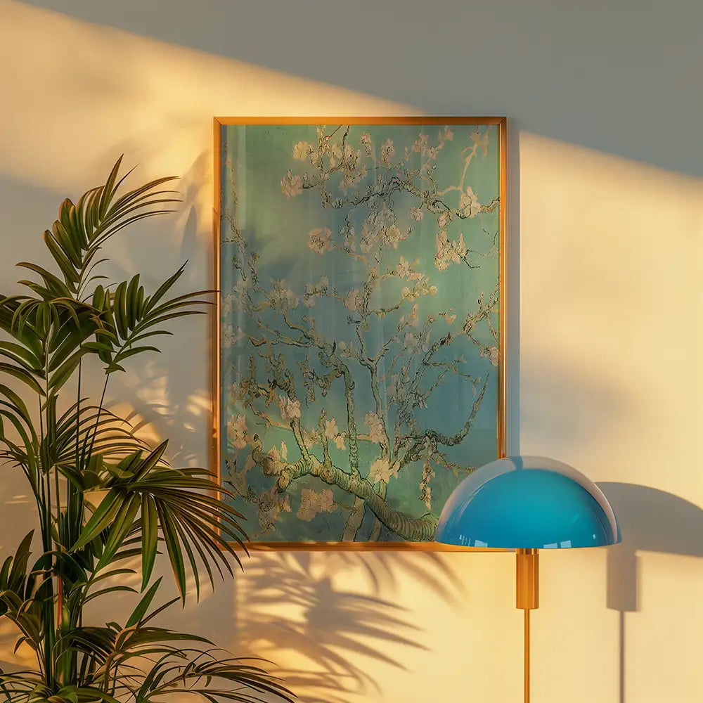 Framed painting of a tree in bloom with a turquoise background, displayed on a wall next to a potted plant and a blue lamp.