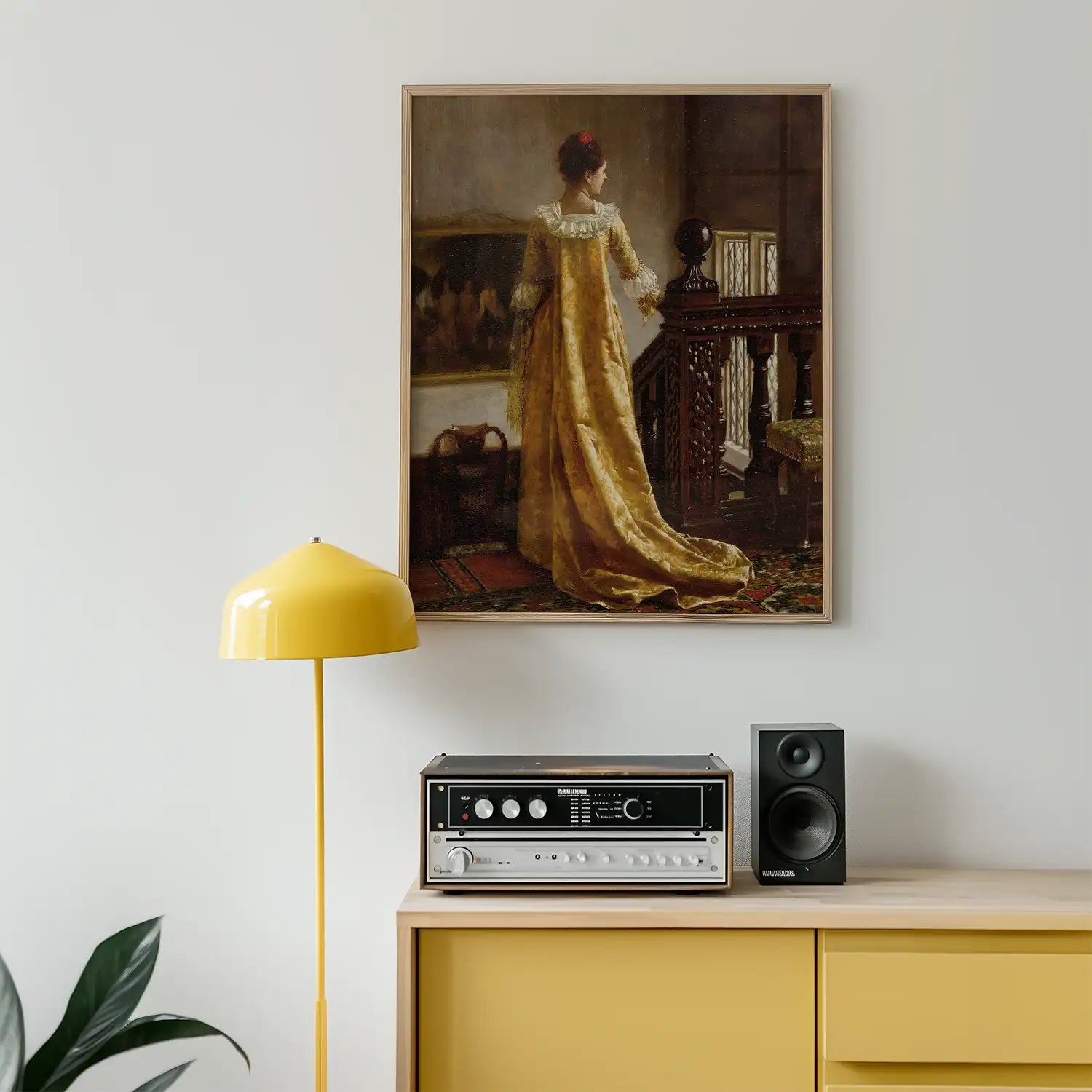 Classic painting of a woman in a yellow gown standing by a staircase, framed and displayed on a wall above a modern console with a yellow lamp and audio equipment.