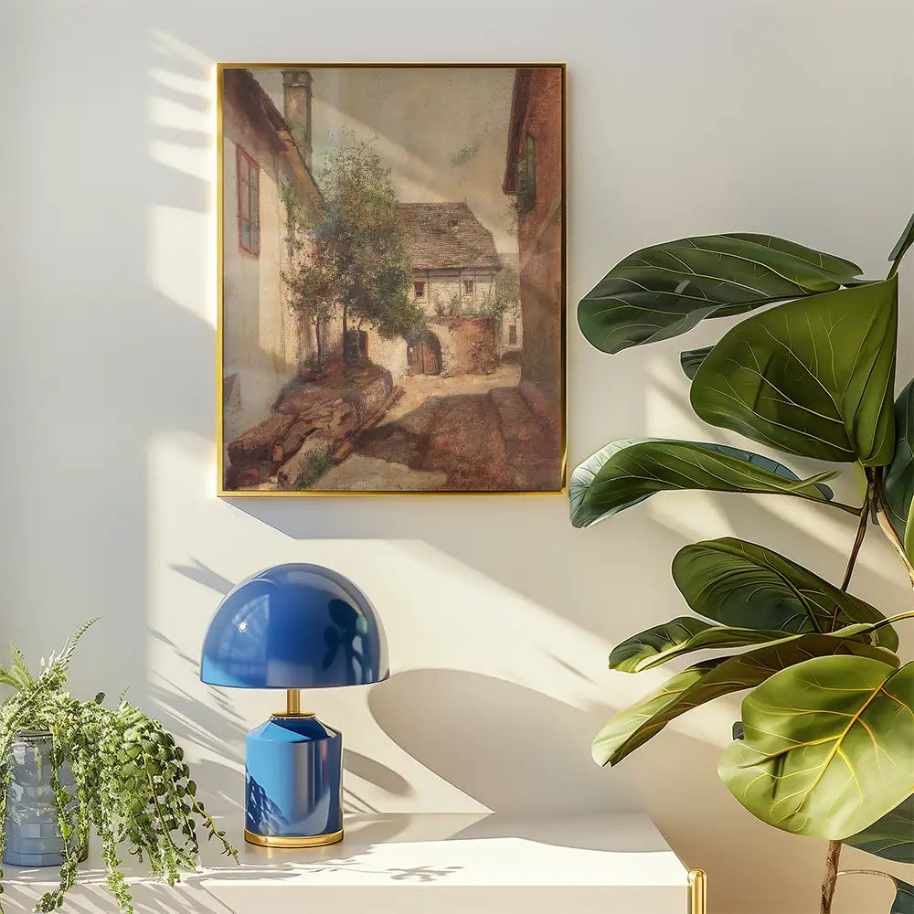 Painting of a serene village scene hung on a wall, accompanied by a blue lamp and leafy plants.