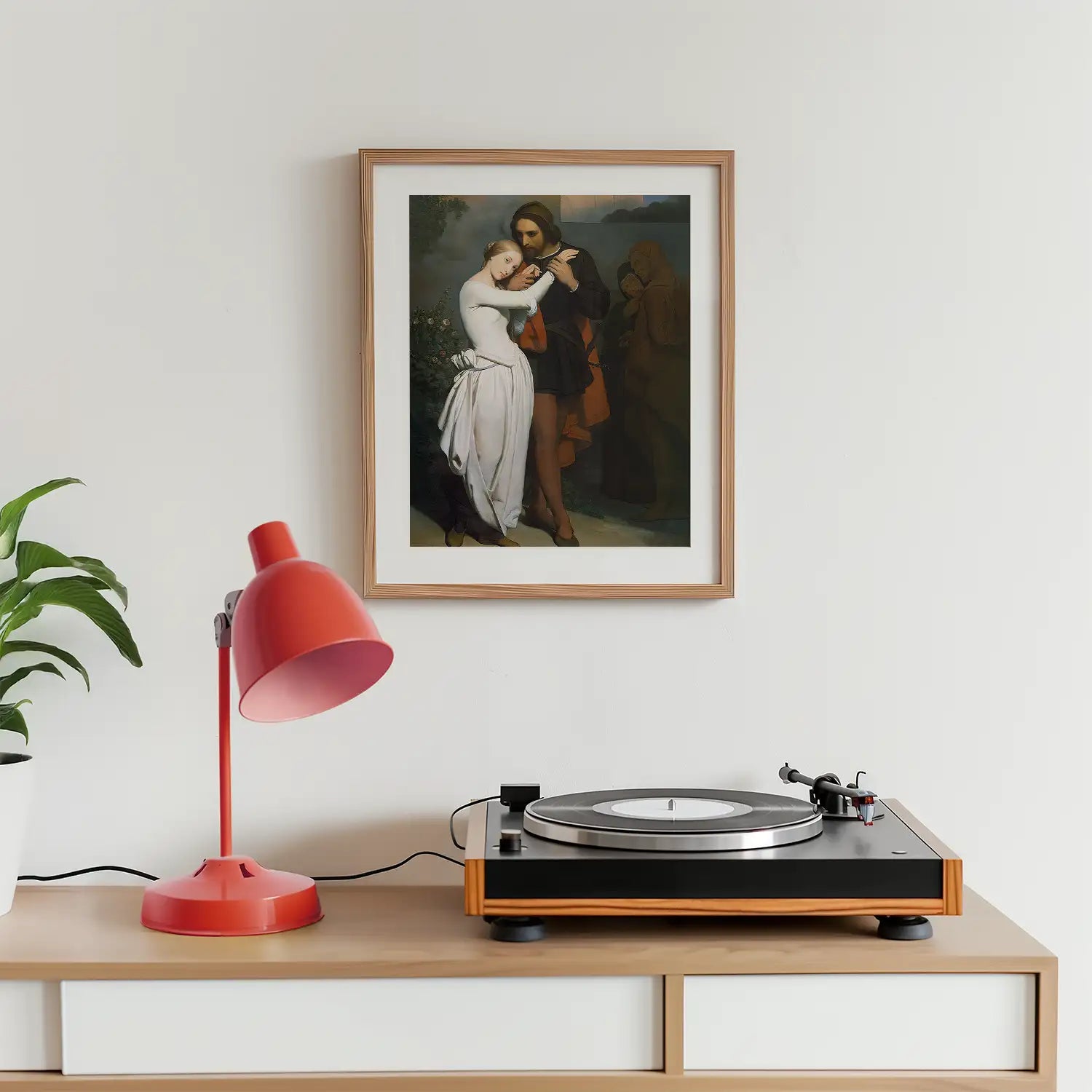 Framed painting of a couple in a romantic embrace displayed on a wall next to a turntable and red lamp.