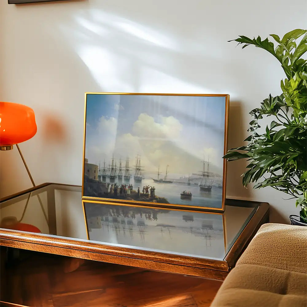 Painting of a coastal scene featuring ships in the harbor, displayed in a gold frame on a wooden table, with a potted plant and an orange lamp in the background.