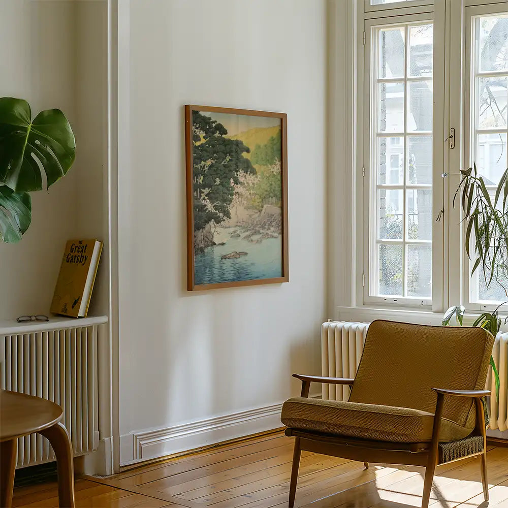 A stylish living room featuring a framed painting of a serene landscape with a river, surrounded by trees, along with a cozy armchair and a potted plant.