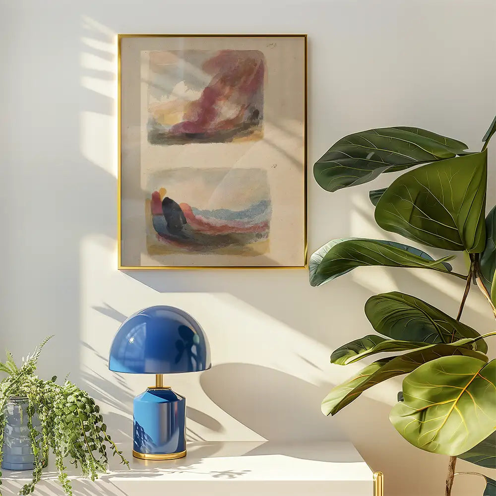 Abstract painting in a gold frame hanging on a wall with a blue lamp and indoor plant beside it.