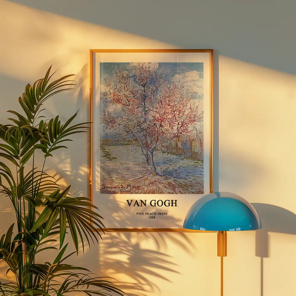 Framed painting of pink peach trees by Van Gogh, 1888, displayed on a wall with a green plant and a blue lamp.
