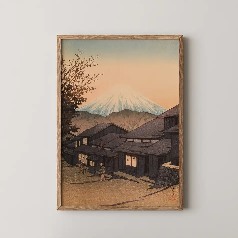A framed painting of a serene landscape featuring Mount Fuji, traditional houses, and a pastel sunset sky.