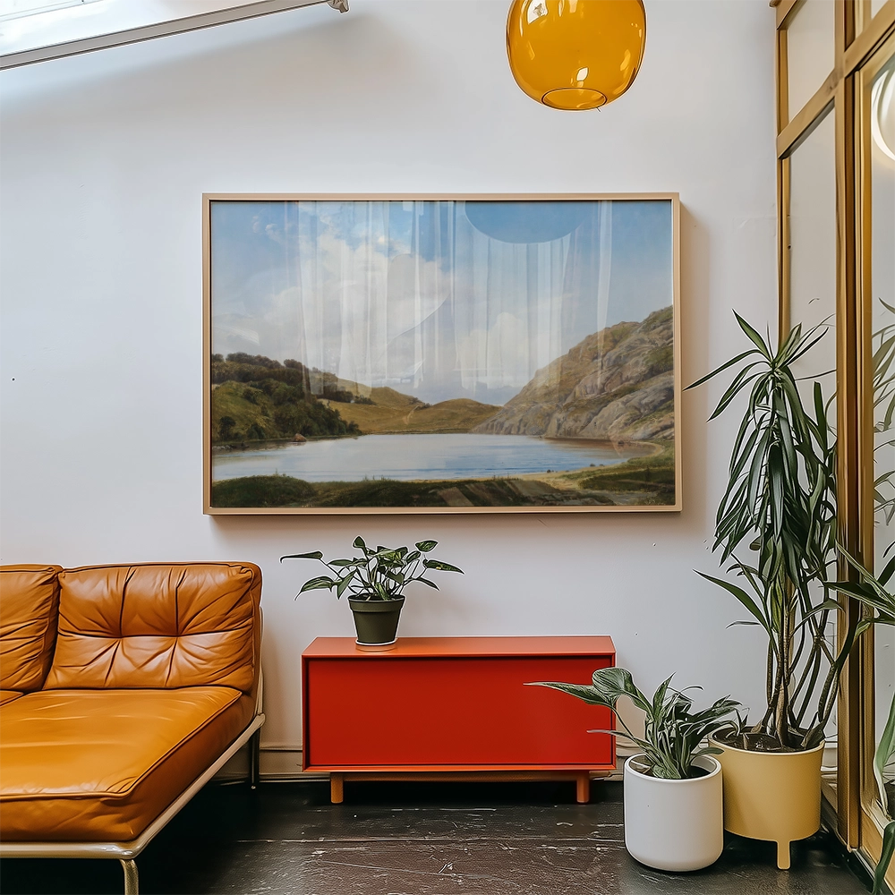 Painting of a serene landscape featuring hills and a lake, framed and displayed in a modern living room setting with an orange couch and potted plants.