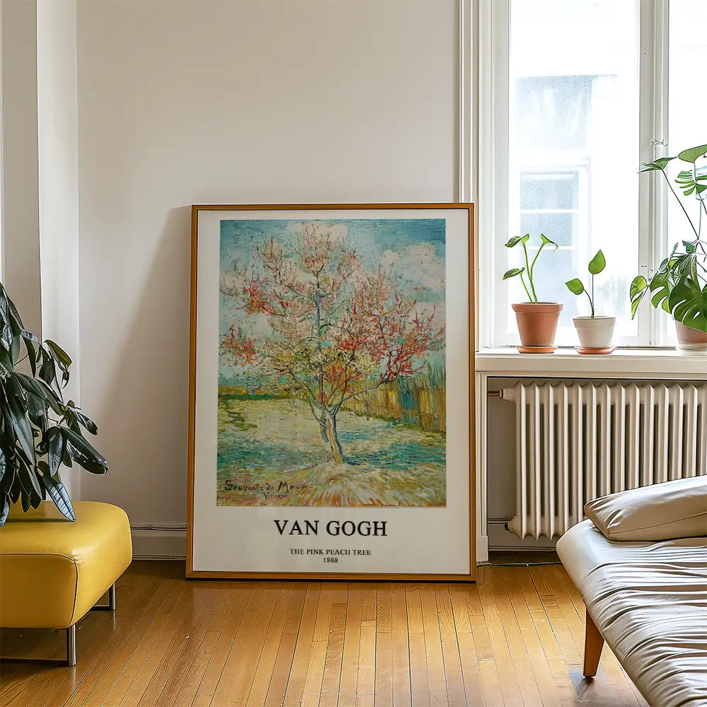 Framed painting of a pink peach tree by Van Gogh, displayed in a bright room with indoor plants and hardwood flooring.