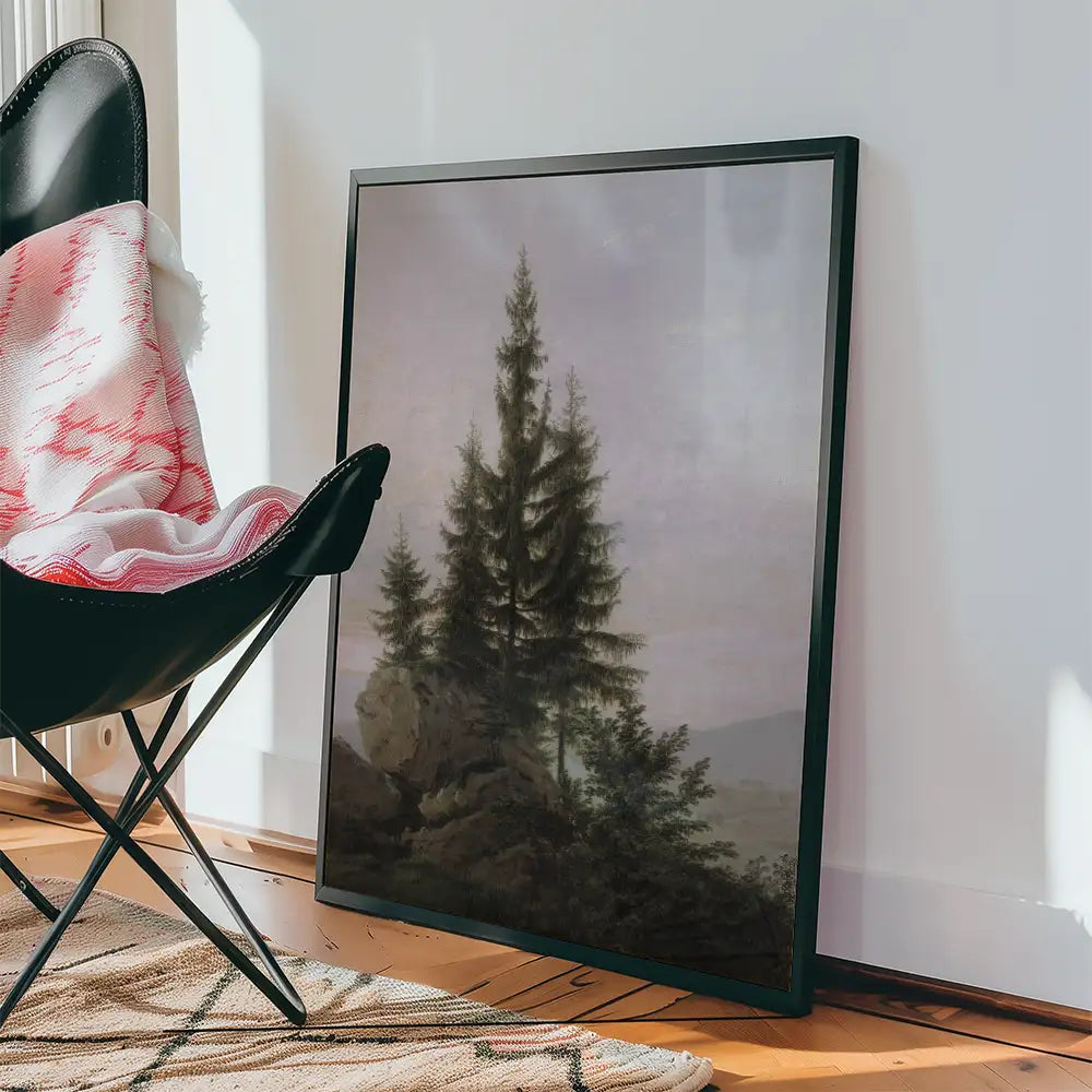 Framed painting of evergreen trees in a serene landscape, leaning against a wall next to a black chair with a decorative throw blanket.