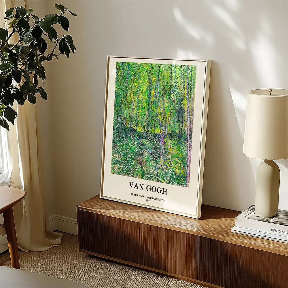 Framed poster of Van Gogh's "Trees and Undergrowth" depicting vibrant green foliage, displayed in a modern interior setting.