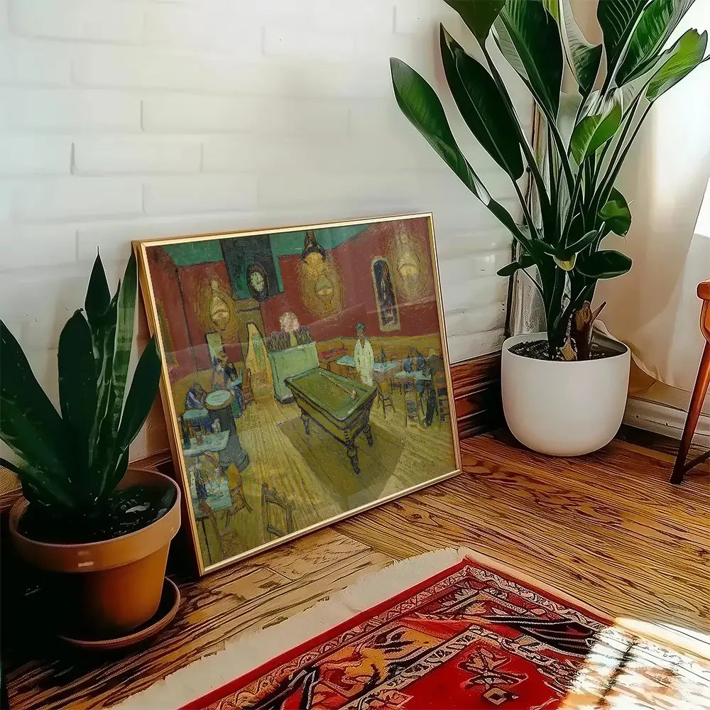 Framed painting displayed on the floor beside a potted plant in a modern interior setting with wooden flooring.