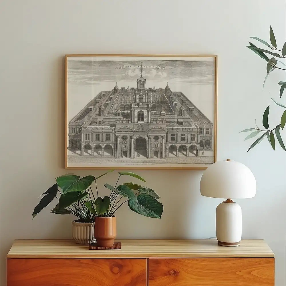 Vintage architectural print of a grand building, framed and displayed on a light-colored wall above a wooden cabinet with plants and a lamp.