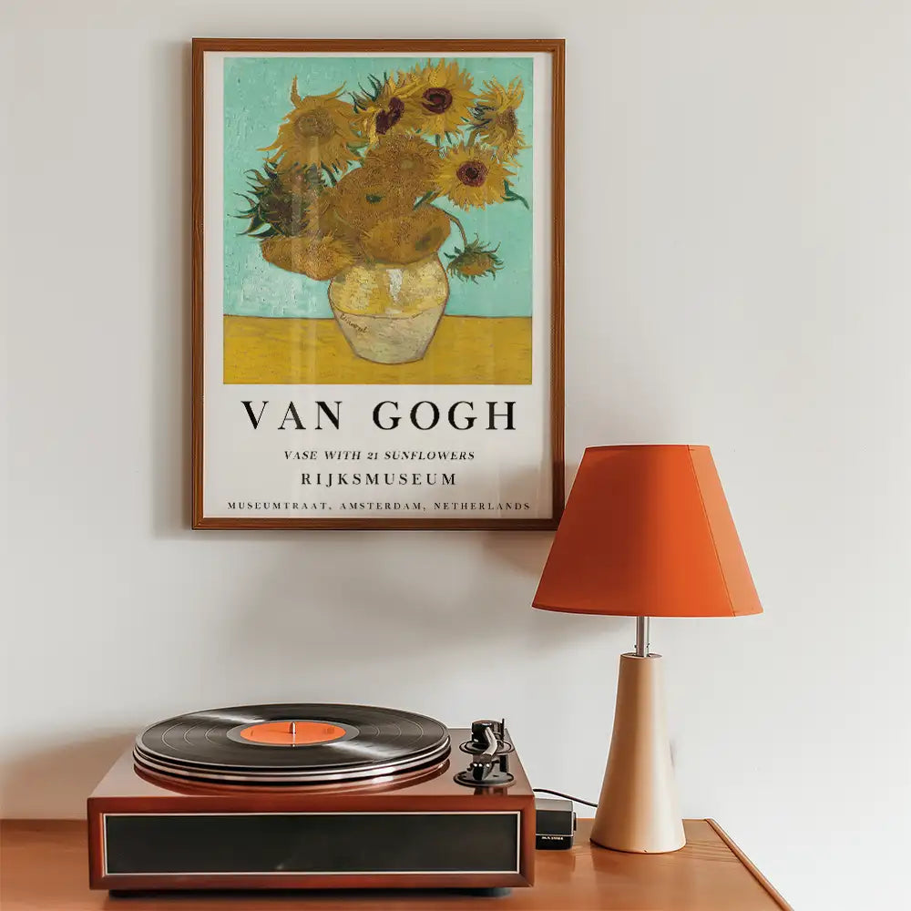 Framed poster of Van Gogh's "Vase with 21 Sunflowers" displayed above a vintage record player and an orange lamp.