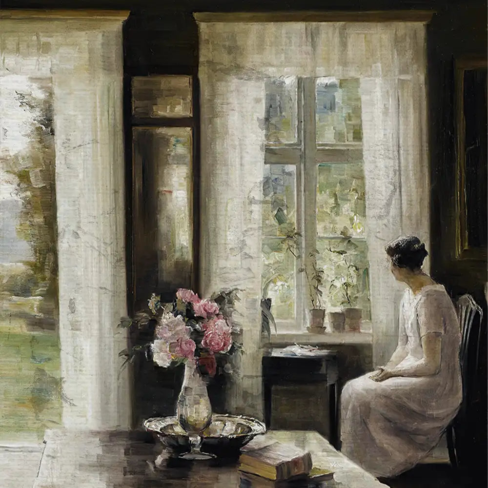A woman sitting by a window with sheer curtains, looking out at a garden, with a vase of flowers and a book on the table beside her.