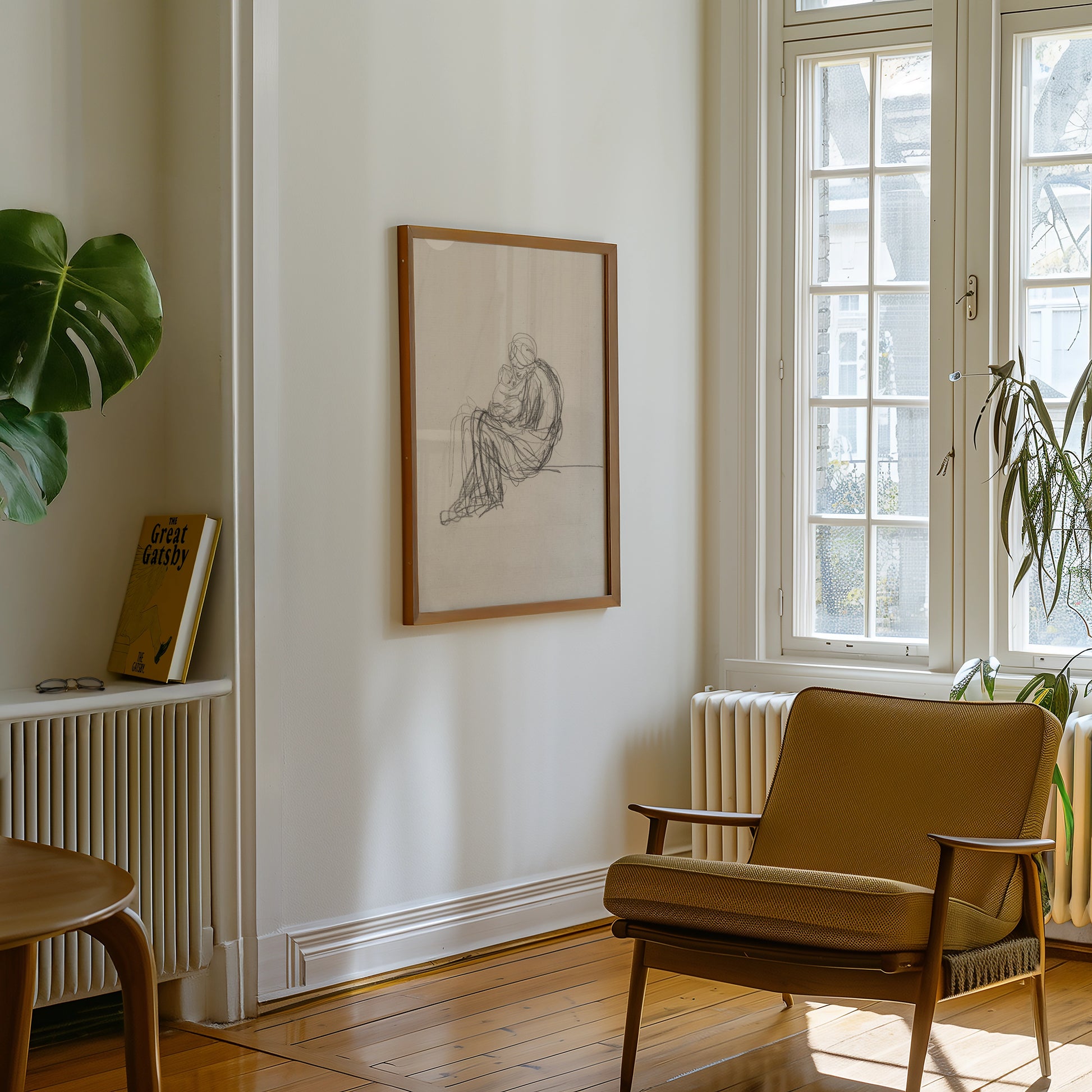Framed pencil drawing of a seated figure, displayed on a light wall beside a green plant and mid-century modern armchair in a bright room.