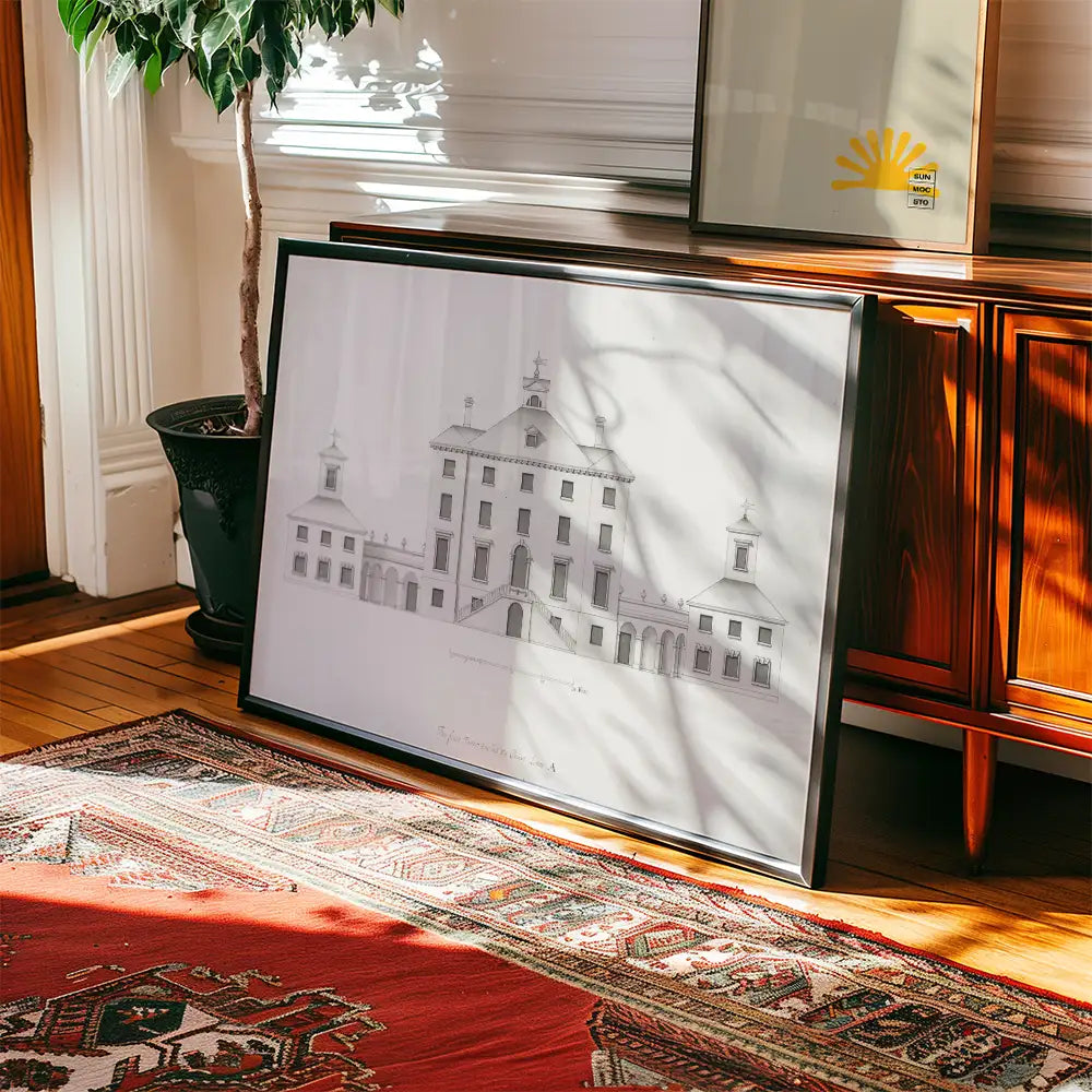Framed architectural illustration of a historic building positioned on a wooden floor beside a plant and decorative rug.