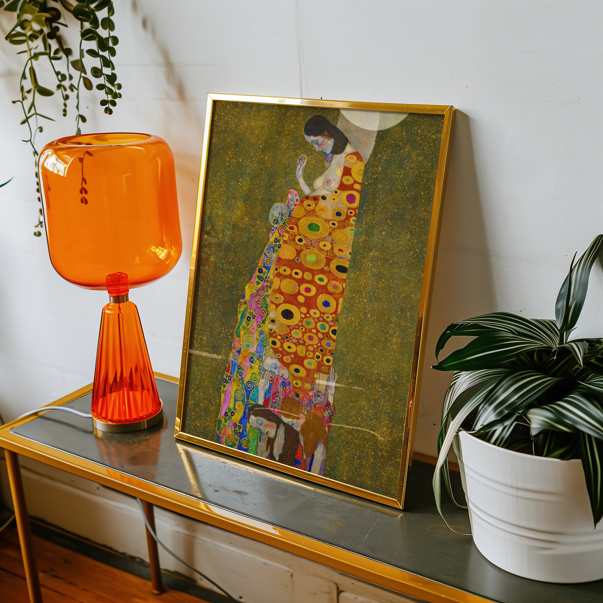 Framed colorful artistic painting displayed on a console table beside an orange lamp and a green plant.