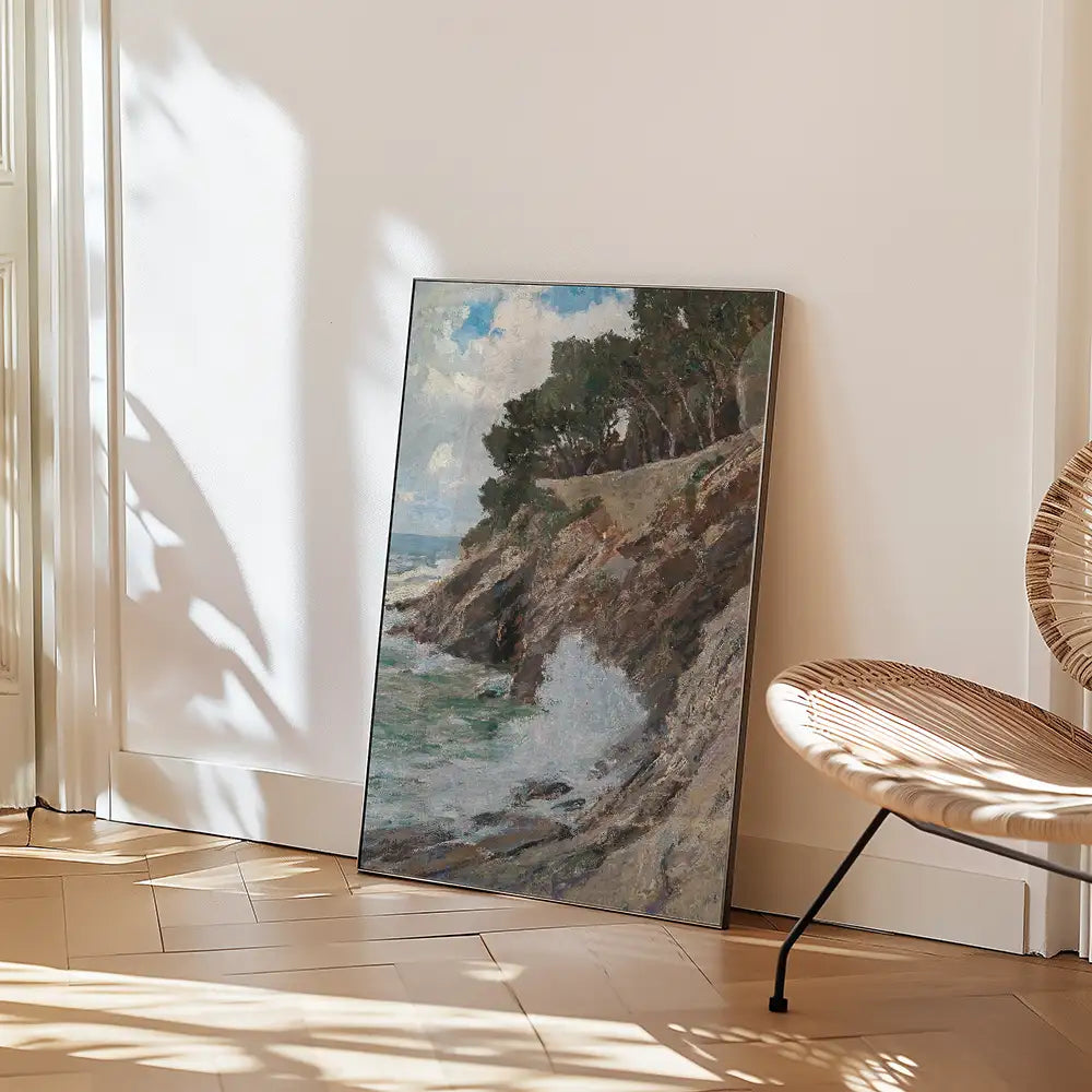 Painting of a coastal landscape with waves crashing against rocky cliffs, propped against a wall beside a modern chair.
