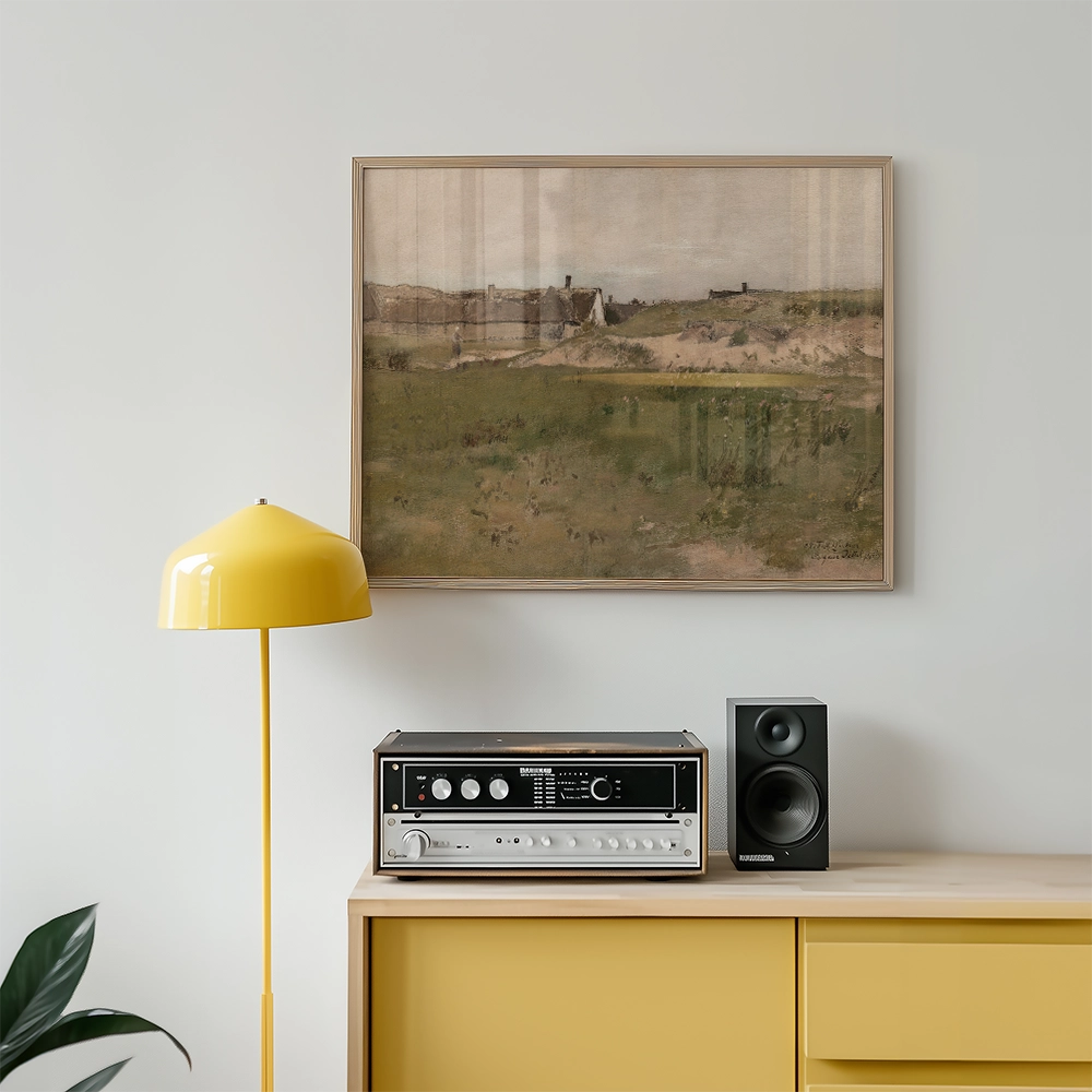 Framed painting of a landscape featuring rolling hills and distant buildings, displayed above a vintage audio system and a yellow floor lamp in a modern living room setting.