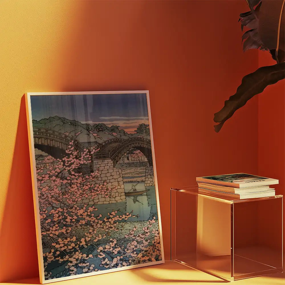 Painting of a serene landscape featuring a stone bridge, cherry blossom trees, and a tranquil body of water, displayed against a warm orange background.